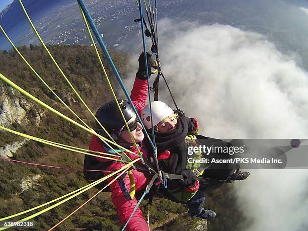 tandem parasailers ride winter thermals above mountains - parasailing imagens e fotografias de stock