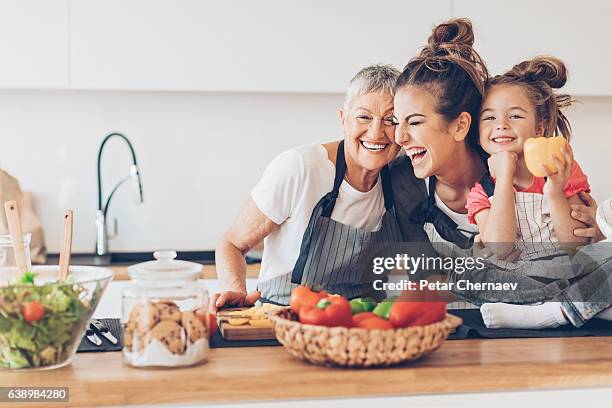 drei generationen frauen lachen in der küche - grandmother stock-fotos und bilder