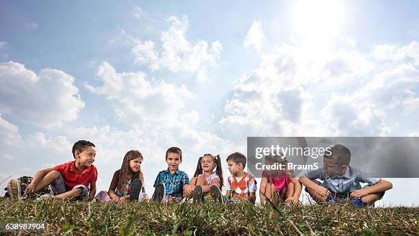 group of cute kids relaxing in grass and communicating. - innocence stock pictures, royalty-free photos & images