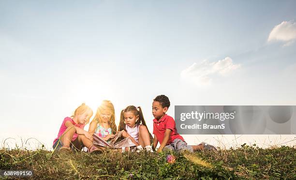 small kids looking at picture book in nature. - kids books stock pictures, royalty-free photos & images