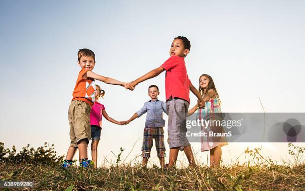 below view of cute friends playing ring-around-the-rosy in nature. - ring around the rosy stock pictures, royalty-free photos & images