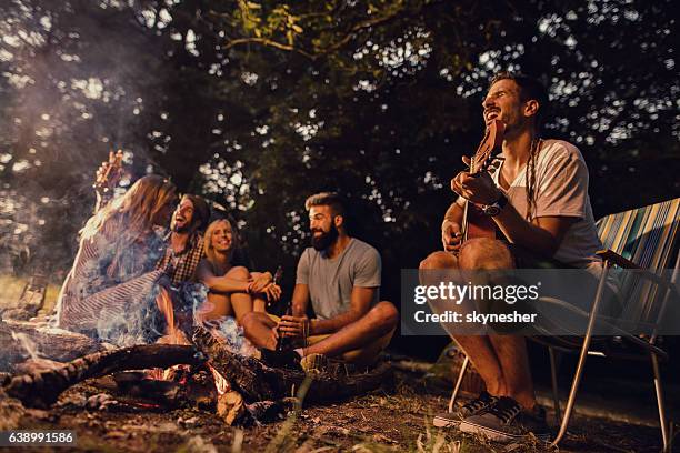 group of friends enjoying with music around campfire in nature. - bonfire 個照片及圖片檔