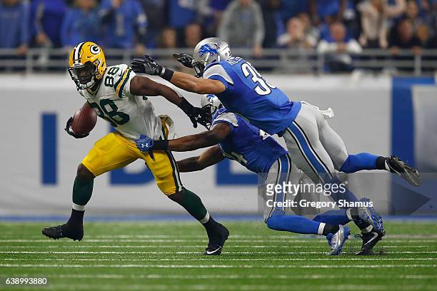 Ty Montgomery of the Green Bay Packers tires to escape the tackle of Miles Killebrew of the Detroit Lions and Nevin Lawson at Ford Field on January...