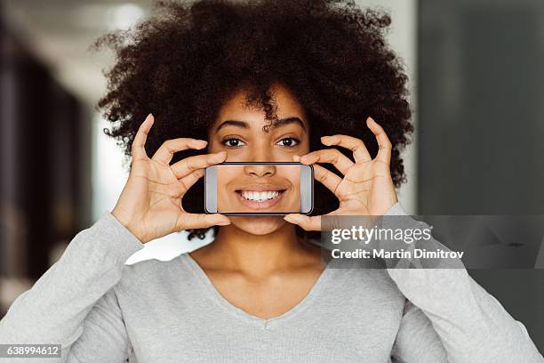 frau mit perfektem, zuschüchterndem lächeln - happy smile with phone stock-fotos und bilder