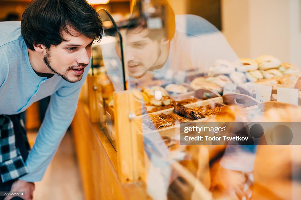 Junger Mann entscheidet, was in einer Bäckerei zu kaufen