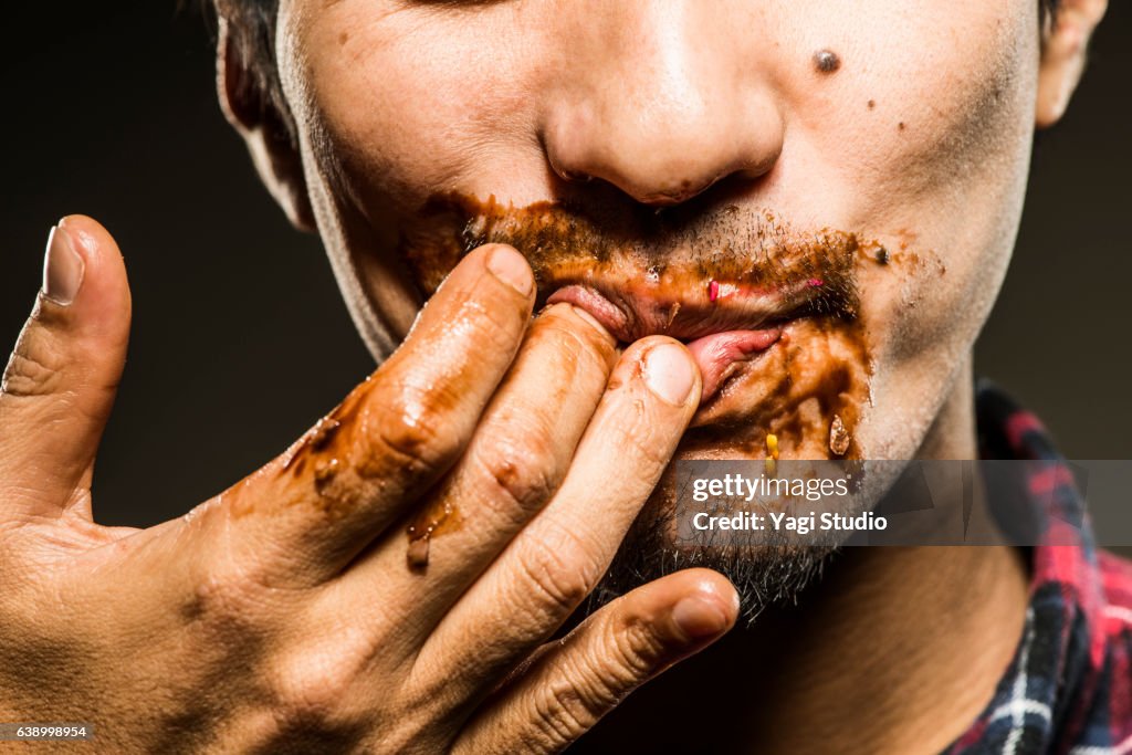Mid adult man licking chocolate,close up shot