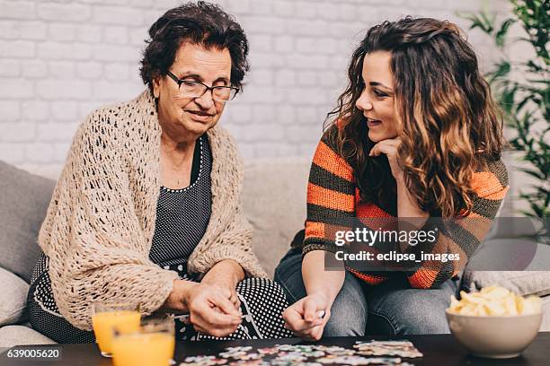 teenage granddaughter helping grandmother with puzzle - senior puzzle stock pictures, royalty-free photos & images