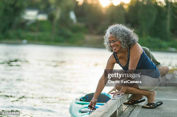 older mature couple putting kayak in the water together - hot wife stockfoto's en -beelden