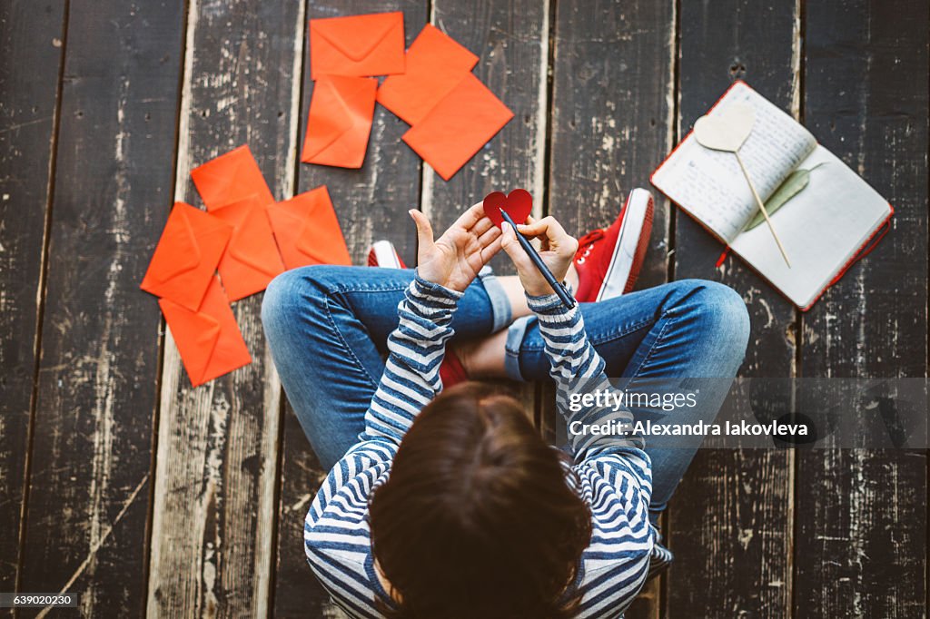 Young woman writing a valentine card - top view