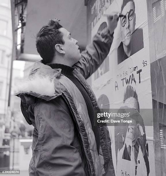 British comedian Dom Joly scrawls graffiti on a poster for his TV show 'Trigger Happy TV', London, United Kingdom, January 2000.