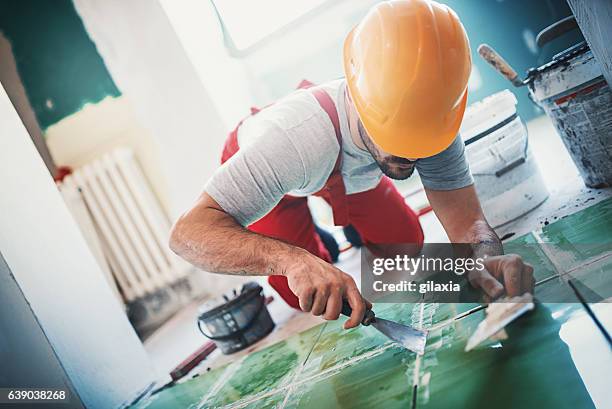 handyman laying ceramic tiles. - positioning stock pictures, royalty-free photos & images