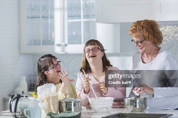 mother and two daughters with down syndrome, baking - down syndrome stock pictures, royalty-free photos & images