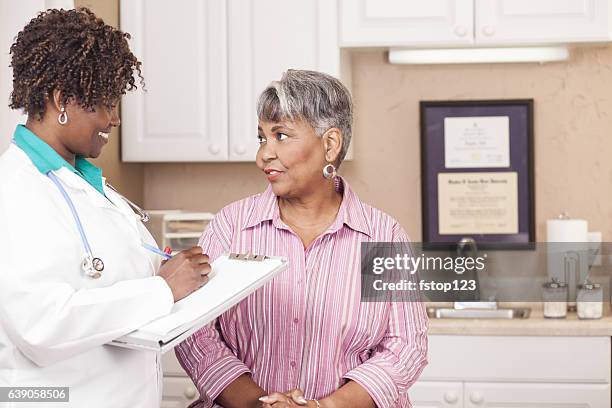 doctor conducts medical consultation with senior adult patient at clinic. - black doctor stock pictures, royalty-free photos & images