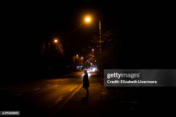 woman standing on pavement at night - street lights stock pictures, royalty-free photos & images