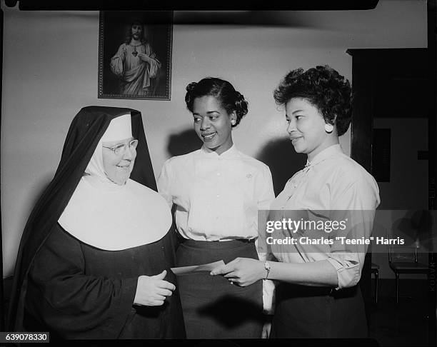 Group portrait of Sister Petrie, Jeanne Holland, and Rebecca 'Becky' Armstrong holding check, for donation to Belvedere Hospital from Kolesque Club,...