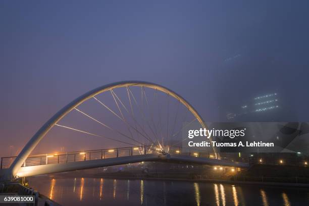 foggy view of a river, lit bridge and skyscraper in incheon, south korea in the evening. - 松島新都市 ストックフォトと画像
