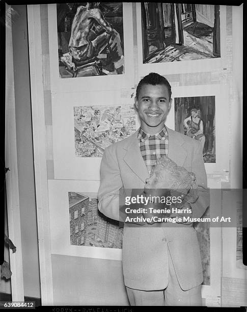 Schenley High School student Albert B. Scott holding ceramic bust in front of paintings at Scholastic Art exhibition, February 1958.