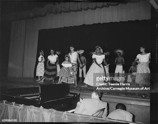 Young women and men from Victor Hereford dancers, and six-year-old Dianne Littlejohn wearing Caribbean style costumes, dancing on stage for Delta...