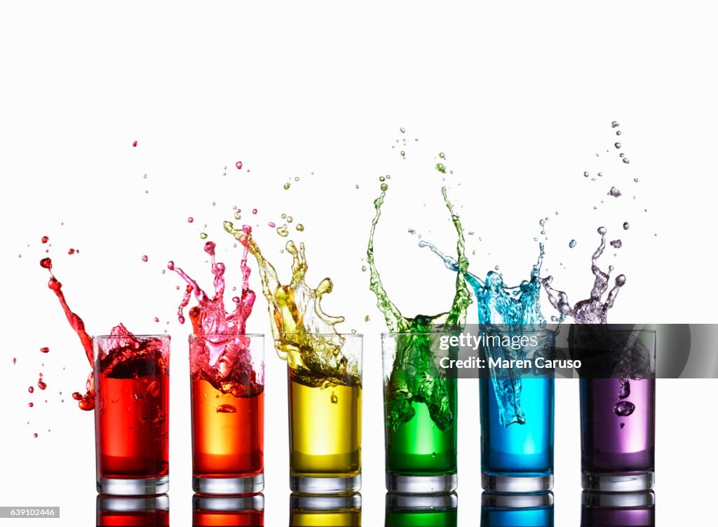 Glasses of colorful liquid splashing