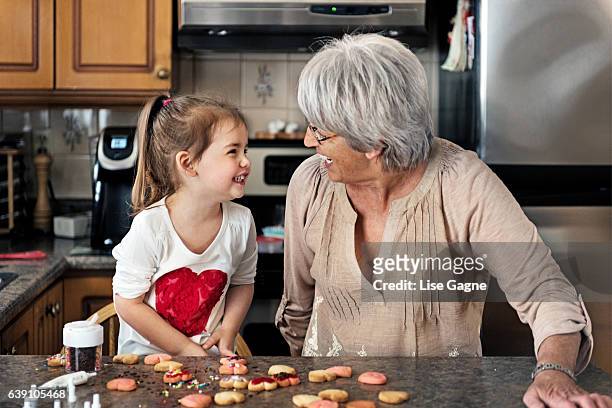 little girl making valentine’s cookie with grandma - lise gagne stock pictures, royalty-free photos & images