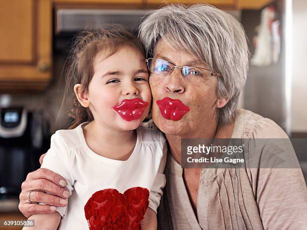 kleines mädchen und großmutter posiert mit großen lippen lollypop - lise gagne stock-fotos und bilder