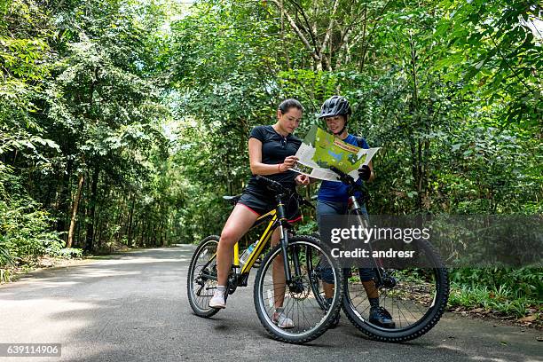 women mountain biking holding a map - singapore map stockfoto's en -beelden