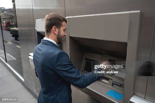 business man withdrawing cash from an atm - man atm smile stock pictures, royalty-free photos & images