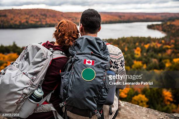 young couple hiking in mountain and relaxing looking at view - travel and canada and fall stockfoto's en -beelden