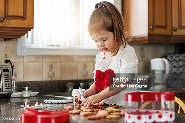 little girl making valentine’s cookie - lise gagne stock pictures, royalty-free photos & images