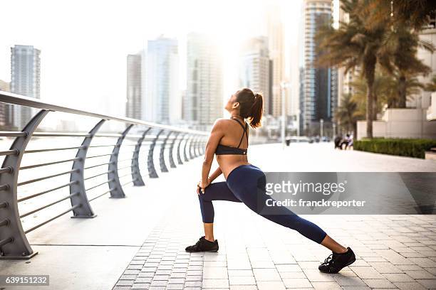 fitness woman doing stretching in dubai marina - kuit menselijk been stockfoto's en -beelden