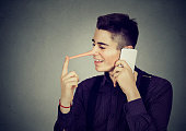 Happy man liar with long nose talking on mobile phone