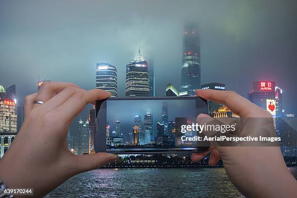 taking pictures with smartphone of shanghai skyscraper in fog - wide angle stockfoto's en -beelden