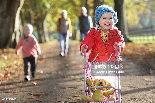 family walking through park in autumn - two kids with cycle imagens e fotografias de stock