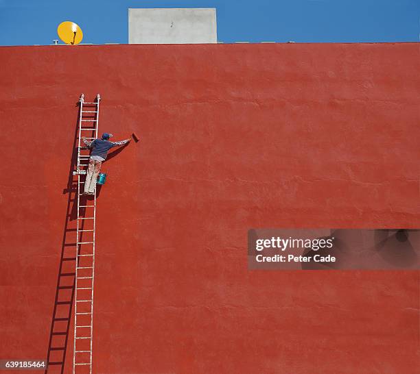 man painting large red wall - red wall stockfoto's en -beelden