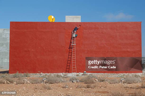 man painting large red wall - painting on wall stock pictures, royalty-free photos & images
