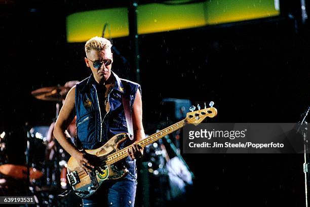 English musician and bass guitarist with U2, Adam Clayton performs live on stage during the band's Zoo TV Zooropa tour at Wembley Stadium in London,...