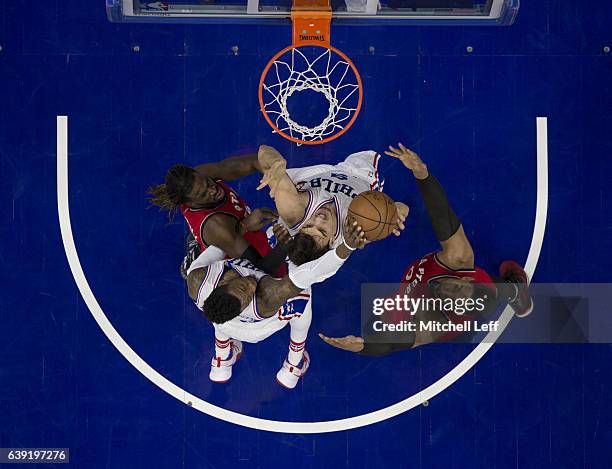 Dario Saric and Robert Covington of the Philadelphia 76ers reach for the ball against DeMarre Carroll and Jared Sullinger of the Toronto Raptors at...