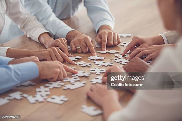 business people putting together jigsaw puzzle - puzzle imagens e fotografias de stock