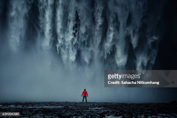 rear view of man standing against skogafoss - skogafoss waterfall stock pictures, royalty-free photos & images