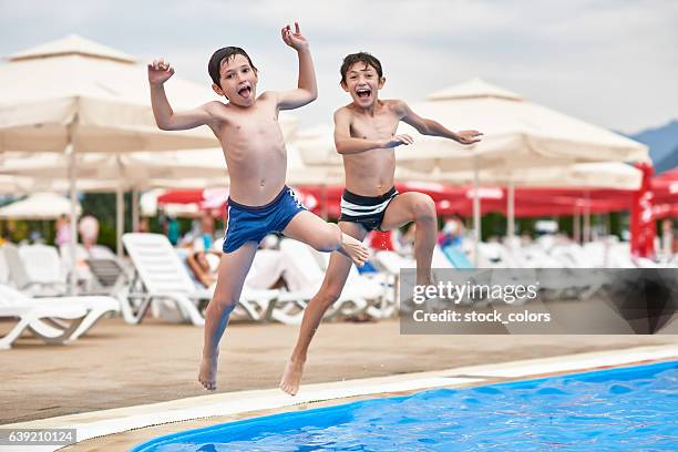 friends enjoying the swimming pool - kid jumping into swimming pool stock pictures, royalty-free photos & images