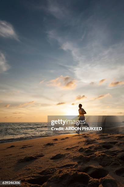 healthy runner man during sunset on the beach - blurred running sunset stock-fotos und bilder