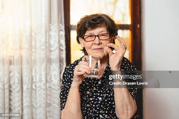 senior woman taking daily dose of pills and medication - eastern european culture bildbanksfoton och bilder