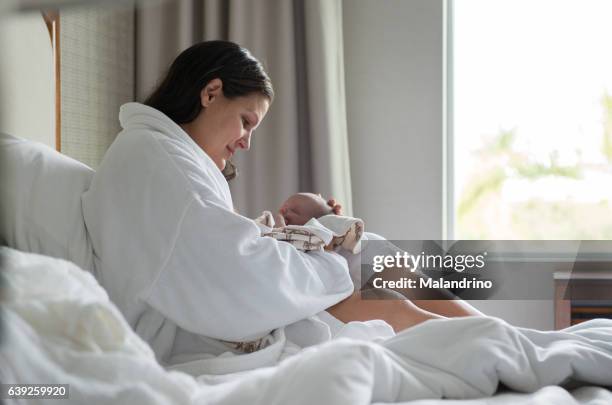 mom holding a baby in her bedroom - home birth stock-fotos und bilder