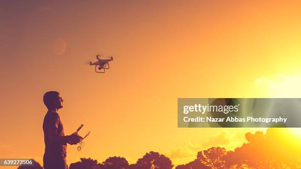 man with his drone and sunset in background. - drones stock pictures, royalty-free photos & images