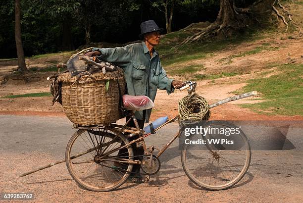 Man goes to fetch firewood with a bicycle near the gateway to Angkor Thom. Angkor Thom is undeniably an expression of the highest genius. It is, in...