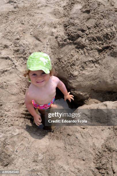 little girl playing with water and sand on the beach - digging beach photos et images de collection