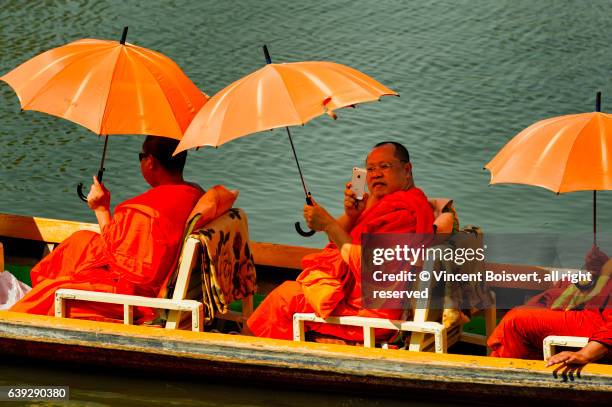 asian monks under parasols in canoe on inle lake, myanmar - sea iphone stock-fotos und bilder