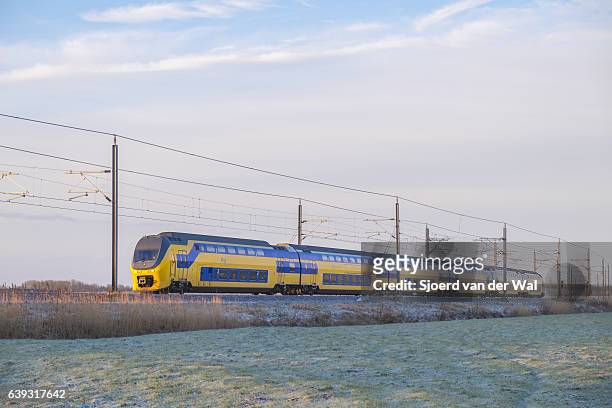 zug der niederländischen eisenbahnen fährt durch gefrorene winterlandschaft - "sjoerd van der wal" stock-fotos und bilder