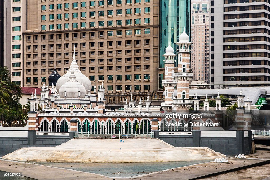 Masjid Jamek mosque with business building in Kuala Lumpur, Malaysia capital city.
