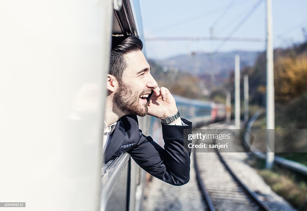 Businessman Talking on The Phone Looking Through Train Window